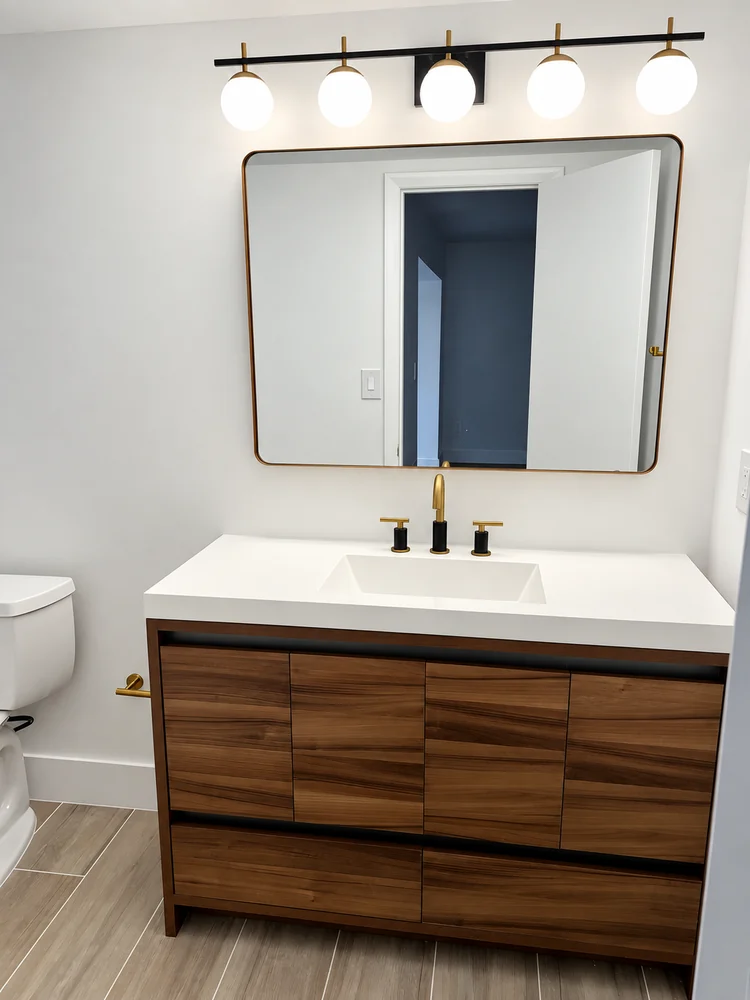 Mueble de baño de nogal con lavabo integrado, grifería de latón, espejo con marco dorado y lámpara de cinco globos