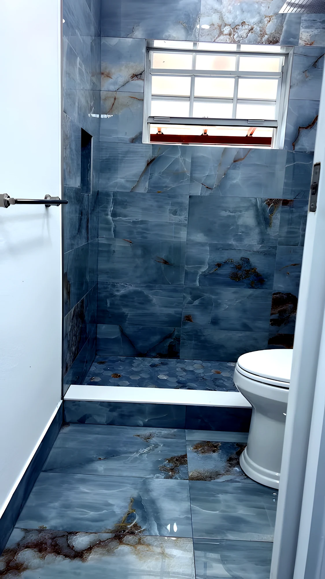 Ducha en ónix azul vista desde la puerta: nicho empotrado, ventana y toallero