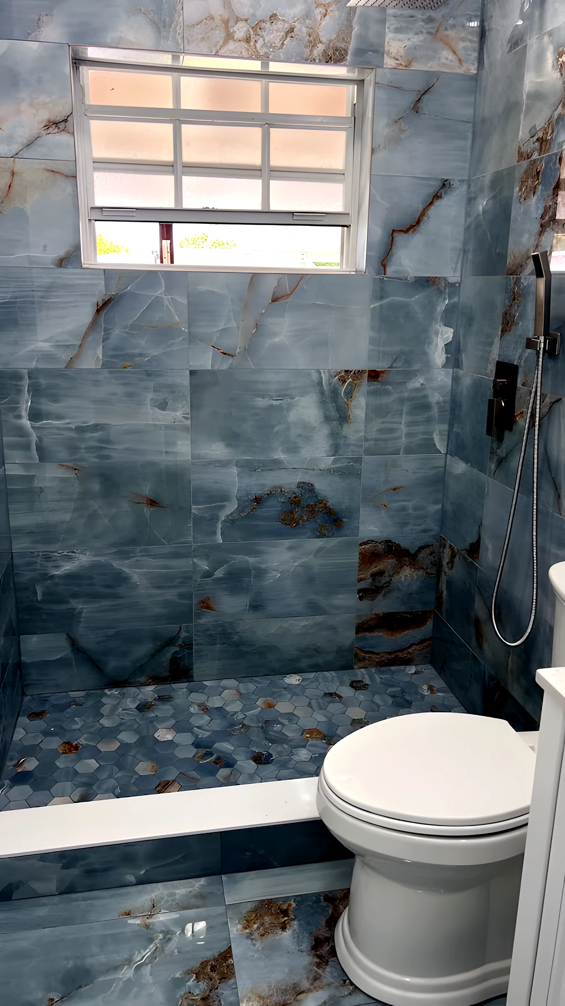 Ducha en porcelanato ónix azul de formato grande, piso de mosaico hexagonal a juego y grifería empotrada