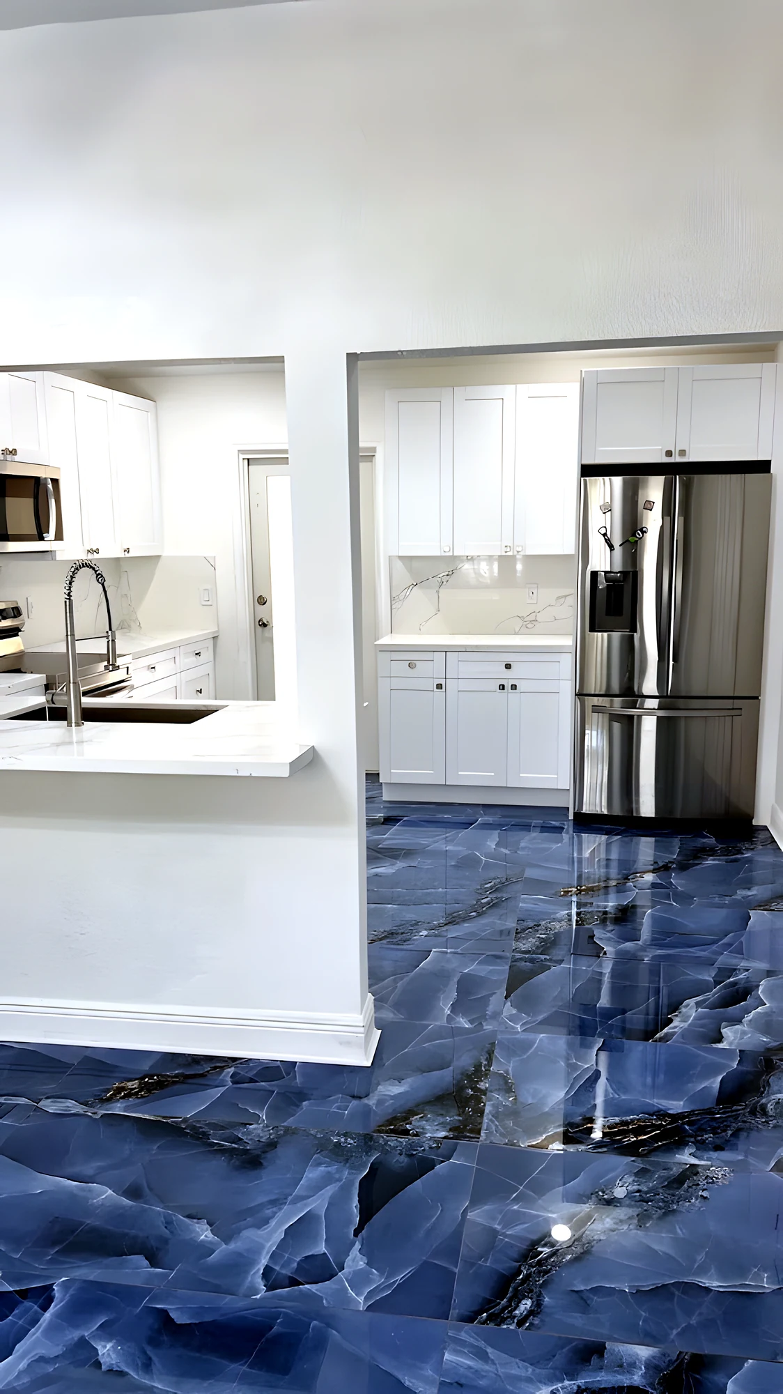 Cocina vista desde el comedor: barra de cuarzo, nevera de acero y piso ónix azul continuo